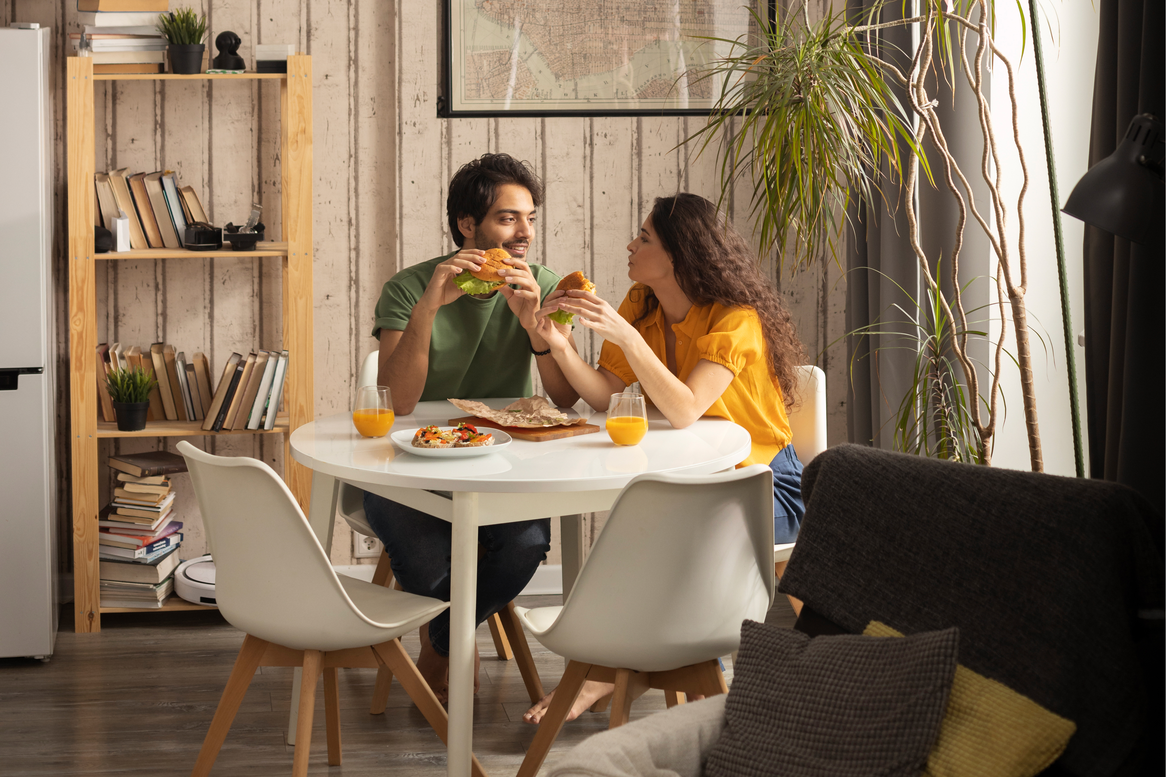 A serene bedroom with a white bed frame, soft linens, and neutral-toned cushions. Elegant wall-mounted lamps add a touch of sophistication, and a doorway leads to an en-suite bathroom